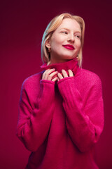 A thoughtful girl posing in front of the magenta background with earphones around her neck. Viva magenta.