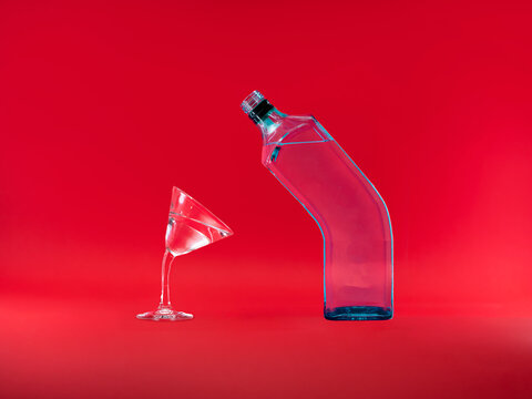 Martini glass and glass bottle leaning towards each other