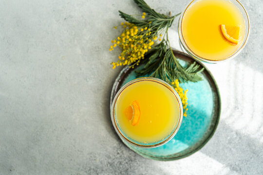 Overhead view of two champagne mimosa cocktails with yellow mimosa flowers