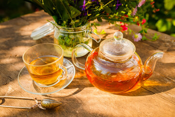 Summer healthy herbal tea in a glass teapot and bunches of medicinal herbs on wooden board. . Phytotherapy. Herbal medicine.