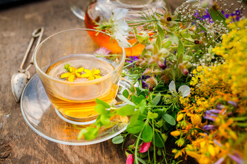 Summer healthy herbal tea in a glass teapot and bunches of medicinal herbs on wooden board. . Phytotherapy. Herbal medicine.