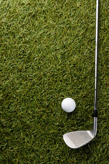 High angle view of white golf ball and golf club on grass with copy space