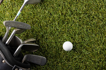 High angle view of white golf ball and golf clubs on grass with copy space