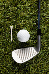 White tee, golf ball and golf club on grass with copy space