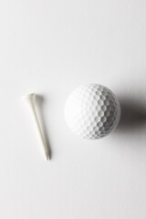 High angle view of white golf ball and golf tee with copy space on white background