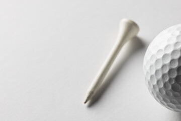 Close up of white golf ball and golf tee with copy space on white background
