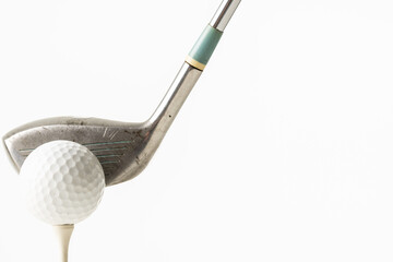 Close up of white golf ball on golf tee and golf club with copy space on white background