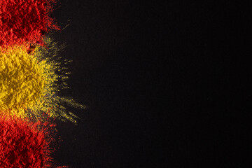 Close up of red and yellow coloured powder and copy space on black background
