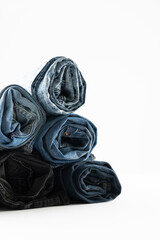 Vertical image of diverse folded jeans lying in stack on white background