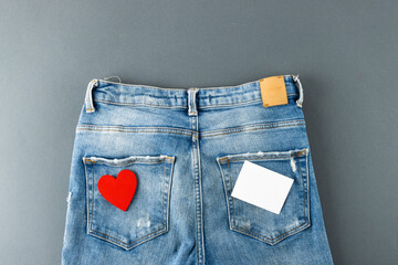 Jeans with heart and post it lying on grey background