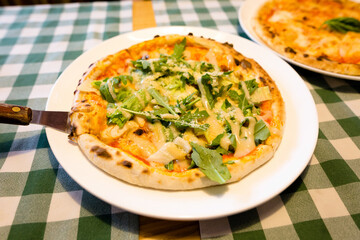 Fresh homemade authentic italian stone oven caesar pizza with arugula, sauce, grilled chicken, herbs and spicy parmesan cheese and margherita. High quality photo.