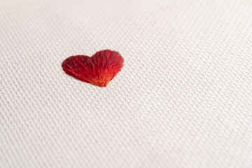 Corazón recién terminado bordado con hilos DMC con degradado rojo sobre tela cuadrillé blanca