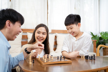 Happy Asian lovely family staying and playing a chess game together in living room in weekend, Group of Asian people playing chess game together in.