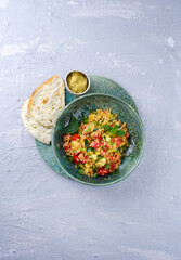 Traditional Moroccan vegetable couscous with pita bread and hummus served as top view on a Nordic Design plate with copy space