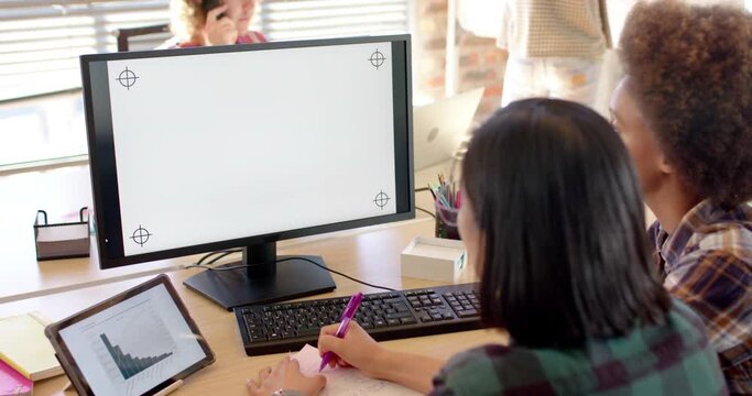 Two happy diverse businesswomen using computer in casual office, copy space on screen, slow motion