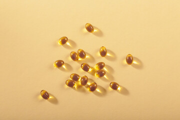 Diet, nutrition, healthy eating concept. Little oil filled yellow softgels capsules of food supplements on beige background.