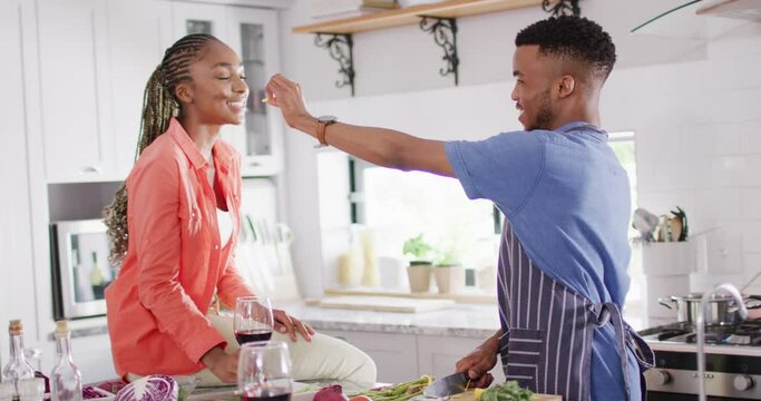Happy african american couple preparing meal in kitchen and trying dish