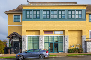 Fototapeta na wymiar Yellow house with windows in Steveston Richmond. Colorful building in a towh at sunny day.