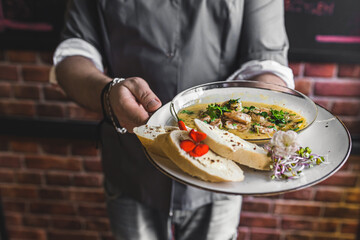 Unrecognisable waiter serving spicy chilli sauce shrimp dish with buttered bread. Restaurant service. Horizontal indoor shot. High quality photo