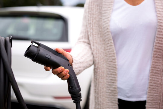 Une conductrice tient le pistolet de chargement de la borne &eacute;lectrique.