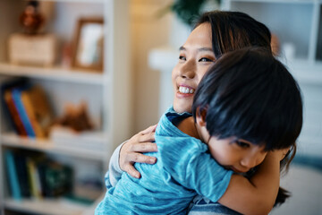 Affectionate Asian mother embracing her small son at home.