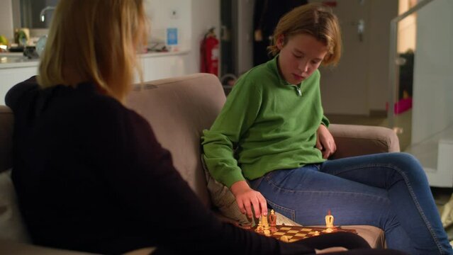 MS - Boy plays chess with his mother at home sitting on the sofa 4