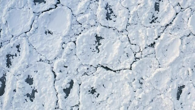 Rising up aerial closeup of snow covering rounded ice chunks floating on Lake Michigan after a Polar Vortex system moved through the Chicago region.