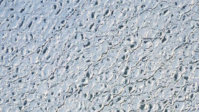 Beautiful aerial footage of scale-like textures created from rounded ice chunks encrusted in snow floating on the water of Lake Michigan.