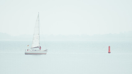 Obraz premium White sailing yacht in foggy mist North Sea in Netherlands