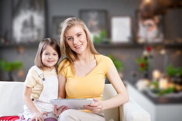 Happy young mom teaching small daughter and reading book together