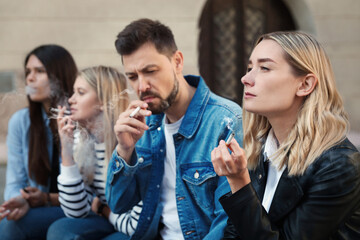 People smoking cigarettes at public place outdoors