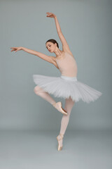 Fototapeta na wymiar Young ballerina practicing dance moves on light grey background
