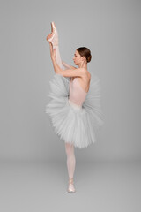 Naklejka premium Young ballerina practicing dance moves on light grey background