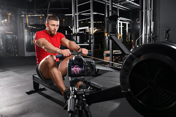 Fototapeta na wymiar Man recording workout on camera at gym. Online fitness trainer