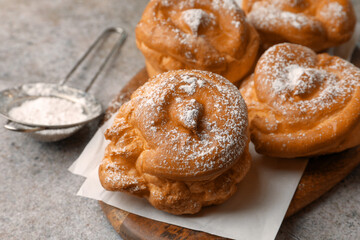 Delicious profiteroles with powdered sugar on grey table, closeup. Space for text