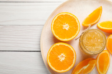 Jar of delicious orange jam and fresh fruits on white wooden table, top view. Space for text