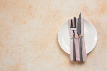 Plate, fork and knife on beige table, top view. Space for text