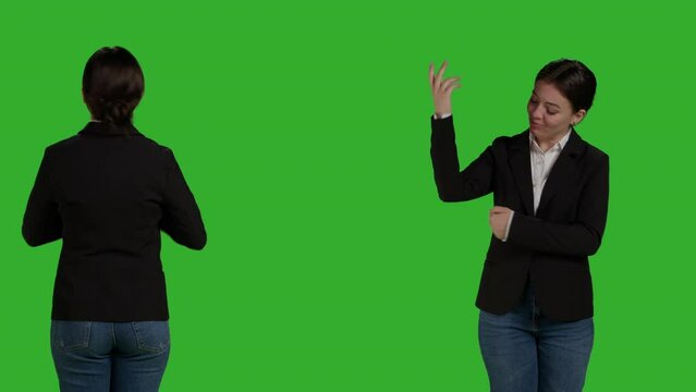 Female office employee pointing sideways to show advertisement over greenscreen studio backdrop, creating example ad on blank copyspace. Young adult with suit showing ad icon in front of camera.