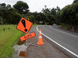 A roadside sign says slips a warning that landslides may be ahead following heavy rainfall.Orange...