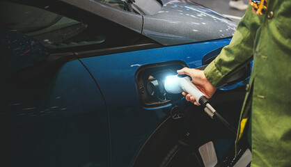 man connecting a charging cable to a car from an electric car charging station.