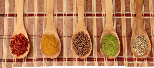 Various colorful spices in wooden spoons