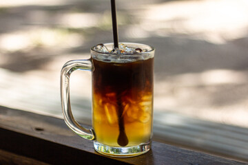 glass of ice americano with honey lemon on wooden table