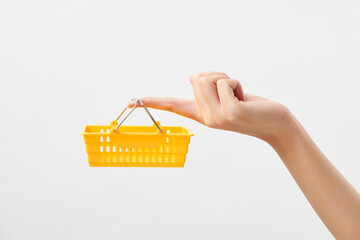 노란색 작은 장바구니를 손가락에 걸치고 들고 있는 여자의 손