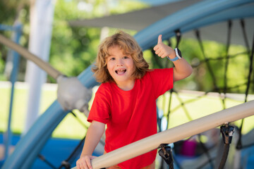 Fototapeta premium Child playing on playground. Kid play on school or kindergarten yard. Healthy summer activity for children. Little boy climbing playground.