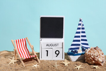 Fototapeta na wymiar Beach holiday composition with sand, seashells, sailboat, deck chair and wooden block calendar with date august 19. Vacation, summertime, creative travel still life