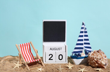 Beach holiday composition with sand, seashells, sailboat, deck chair and wooden block calendar with date august 20. Vacation, summertime, creative travel still life