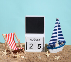 Beach holiday composition with sand, seashells, sailboat, deck chair and wooden block calendar with date august 25. Vacation, summertime, creative travel still life