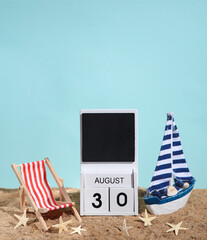 Beach holiday composition with sand, seashells, sailboat, deck chair and wooden block calendar with date august 30. Vacation, summertime, creative travel still life
