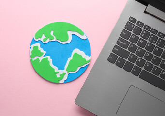 Laptop with earth planet on pink background