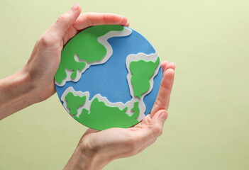 Female hands hold planet earth on green background. Save the planet